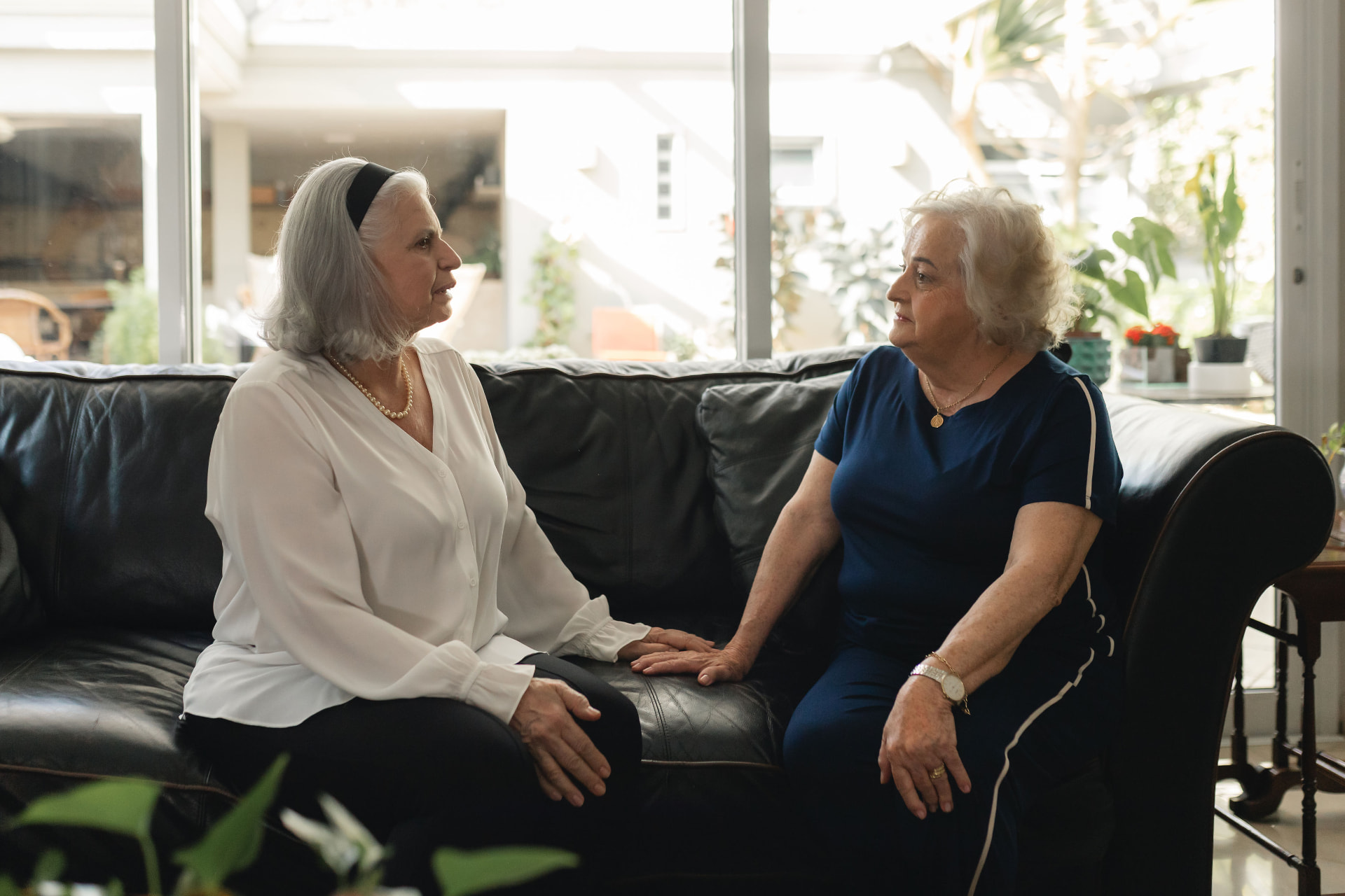 Duas senhoras conversando sentadas no sofá da sala, em um ambiente claro e acolhedor